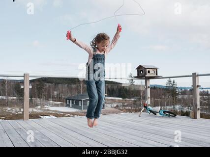 Mädchen springt auf ihrem Balkon draußen in Schweden Stockfoto