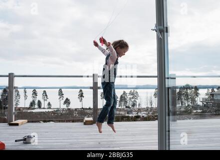 Mädchen springen auf ihrem Balkon zu Hause mit Blick auf das Meer Stockfoto