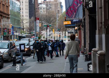 Kunden, die während der Coronavirus-Pandemie im März 2020 online auf dem Broadway & 12th Street, New York City warten. Stockfoto