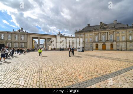 Dänische Polizei und Wachleute werden auf dem Gelände des Schlosses Amalienborg gesehen, während Touristen an einem der Gebäude der Königlichen Regierung vorbeifahren. Stockfoto