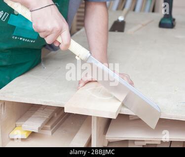 Die Hände des Tischlers. Junge bärtige Hüpfer in einer Zimmermannswerkstatt sägen kühle japanische Säge. Stockfoto