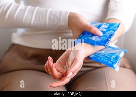 Nahaufnahme der Frau, die an ihrem schmerzhaften Handgelenk eine kalte Kompression anwendet, die durch längere Arbeit am Computer, Laptop und selektive Fokussierung auf die Hand verursacht wird. Karpaltunn Stockfoto