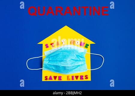 Quarantäne. "Stay Home Save Lives"-Ausdruck auf dem gelben Hintergrund und der Einwegmaske. Stockfoto