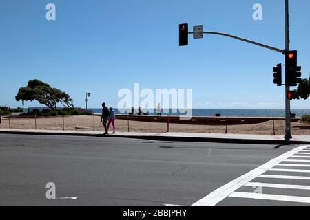 Laguna Beach, CA/USA - 23. März 2020: Ein einsames Paar spaziert am Laguna Beach vorbei, der eingezäunt und gesperrt ist, um die Schließung von COVID-19 durchzusetzen Stockfoto