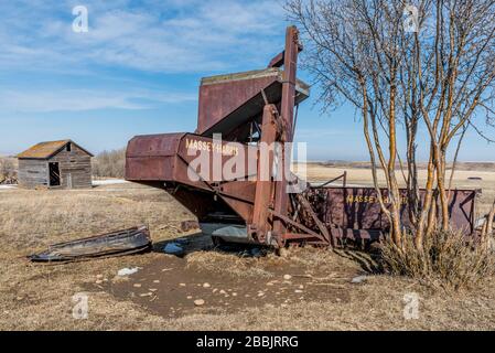 Wymark, SK, Kanada - 30. März 2020: Mähdrescher und Getreidespeicher des Typs Massey-Harris, die in einem Feld in Saskatchewan, Kanada, aufgegeben wurden Stockfoto