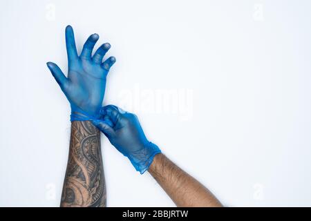 Ein Mann, der die Variation von Blue Latex Glove, die Herstellung von Gummihandschuhen, die menschliche Hand hält, trägt einen medizinischen Handschuh, einen Handschuh, einen isolierten Stockfoto