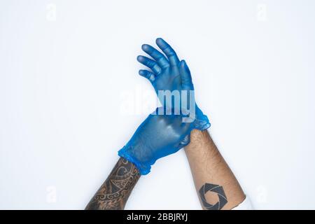 Ein Mann, der die Variation von Blue Latex Glove, die Herstellung von Gummihandschuhen, die menschliche Hand hält, trägt einen medizinischen Handschuh, einen Handschuh, einen isolierten Stockfoto