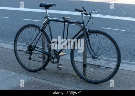 Nahansicht eines schwarzen Bycycycle, der auf einen Fahrradständer außerhalb eines Shupermarket gesperrt ist Stockfoto