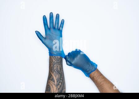 Ein Mann, der die Variation von Blue Latex Glove, die Herstellung von Gummihandschuhen, die menschliche Hand hält, trägt einen medizinischen Handschuh, einen Handschuh, einen isolierten Stockfoto