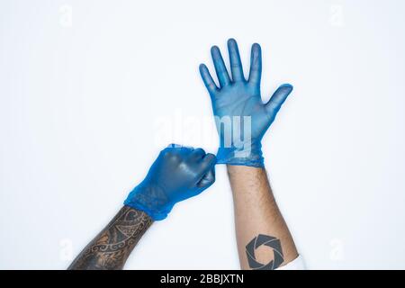 Ein Mann, der die Variation von Blue Latex Glove, die Herstellung von Gummihandschuhen, die menschliche Hand hält, trägt einen medizinischen Handschuh, einen Handschuh, einen isolierten Stockfoto