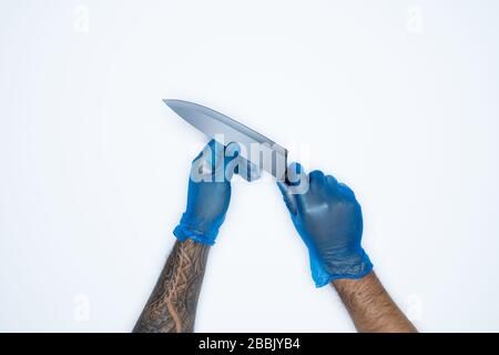 Ein Mann und Gesten in blauem Gummihandschuh zeigen Messer isoliert auf weißem Hintergrund. Stockfoto