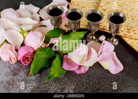 Matzos ungesäuertes Brot auf einer kiddush Tasse Wein Passahfeier mit Matzo ungesäuertem Brot aus frischer rosafarbener Rosenblüte Stockfoto