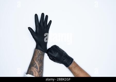 Ein Mann, der die Variation des schwarzen Latexhandschuhs, die Herstellung von Gummihandschuhen, die menschliche Hand hält, trägt einen medizinischen Handschuh, einen Handschuh, einen isolierten Stockfoto