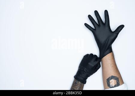 Ein Mann, der die Variation des schwarzen Latexhandschuhs, die Herstellung von Gummihandschuhen, die menschliche Hand hält, trägt einen medizinischen Handschuh, einen Handschuh, einen isolierten Stockfoto