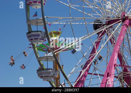 Ein Riesenrad und eine Schaukel fahren auf einer Sommermesse Stockfoto