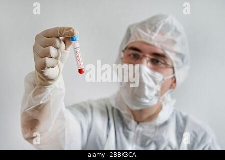 Ein junger Wissenschaftler untersucht einen Bluttest auf Coronavirus. Diagnose 2019-ncov. Positives Bluttestergebnis für Kovid 19. Kaukasischer Arzt mit a B. Stockfoto