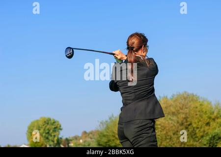 Weiblicher Golfspieler, der nach der Arbeit im Business-Outfit spielt Stockfoto