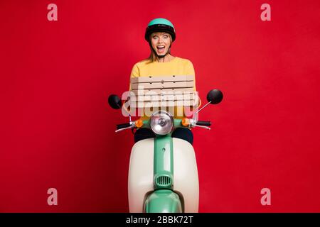 Portrait von ihr schön verblüffte fröhliche fröhliche Freundin, die auf Moped sitzt, in Händen stapelt Dessert Verkaufsrabatt isoliert auf hell Stockfoto