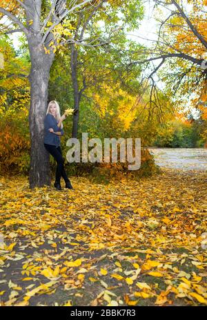 Schöne Frau lehnt sich im Herbstpark an Baum Stockfoto