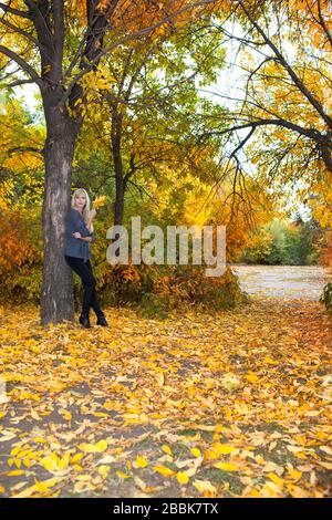 Schöne Frau lehnt sich im Herbstpark an Baum Stockfoto