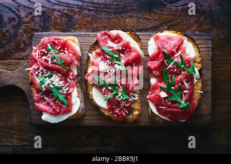 Gourmet-Bruschetten mit rohem Rindfleisch Carpaccio, Mozzarella und arugula italienische Küche Stockfoto