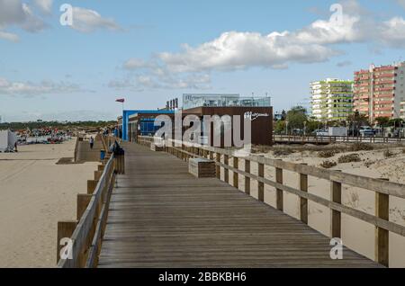 Monte Gordo, Portugal - 18. November 2019: Urlauber, die den Boardwalk über die weichen Sanddünen am Strand von Monte Gordo an den coas der Algarve nutzen Stockfoto