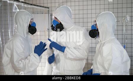 Gruppe von Ärzten in Schutzanzügen, die ernsthafte Diskussionen führen. Stockfoto