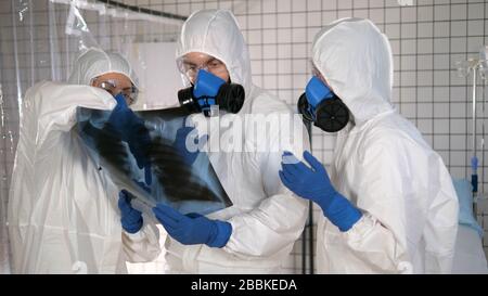 Laborärzteteam in Schutzkleidung mit Blick auf den Röntgenstrahl der Lunge. Stockfoto