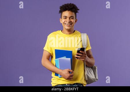 Zurück zur Schule, Hochschulkonzept. Portrait von fröhlichen jungen, gutaussehenden männlichen Studenten, die Rucksack auf der Schulter tragen, Notizbücher halten und Bücher studieren Stockfoto