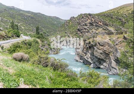 Landschaft mit den Schluchtufern der Straße 6 und Kawarau, in hell bewölktem Quelllicht auf Roaring Meg Powerstation, Otago, South Island, Neuseeland geschossen Stockfoto