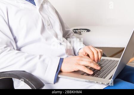 Reifer Arzt, der an Laptops und Medikamentenfällen arbeitet, um Rezepte in seiner Klinik zu machen. Mann bereitet Online-Internet-Rezept vor Stockfoto
