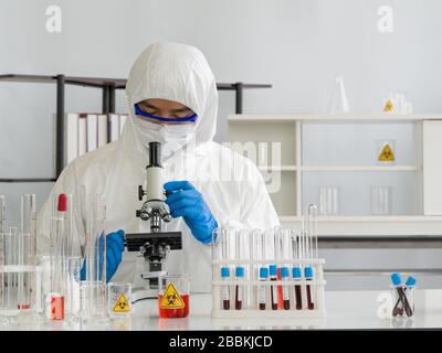 Forscher verwenden Mikroskope, um Blutproben infizierter Menschen zu untersuchen. Coronavirus Disease 2019 (COVID-19) Testverfahren in einem Labor Stockfoto