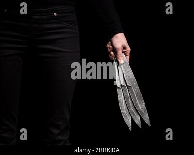 Mädchen hält in der Hand Stahl Wurfmesser auf schwarzem Hintergrund Stockfoto