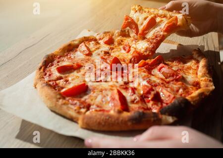 Große Pizza steht in einem Café in der Nähe auf einem Tisch. Italienische Pizza auf Stücke geschnitten. Stockfoto