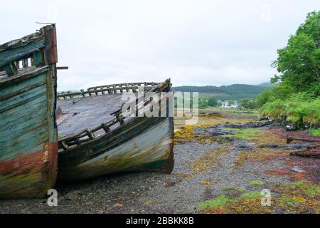 Ein interessanter Ort auf Mull Island, in den Hebriden in Schottland. Zwei alte, einst schöne und bunte Holzboote, die am Strand liegen, wurden zu einem Wahrzeichen Stockfoto