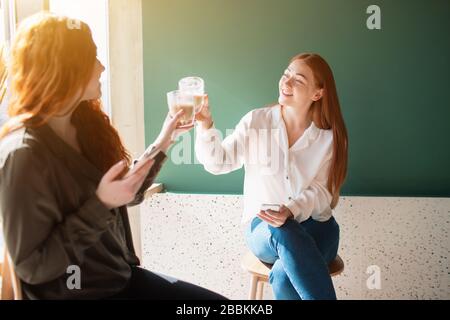 Junge Frauen reden im Café. Weibliche Modelle trinken Kaffee und lächeln. Stockfoto