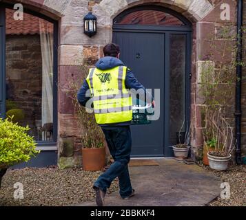 East Lothian, Schottland, Großbritannien, 1. April 2020. Lokale Lebensmittellieferungen während der Pandemie von Covid-19 Coronavirus: Die Molkereien der Yester Farm beginnen zweimal wöchentlich mit kostenlosen Hauslieferungen an Einwohner in East Lothian. Yester Mains ist ein Familienbetrieb, der preisgekrönte Molkereiprodukte für Handwerker liefert. Sie wurden mit Aufträgen überflutet. Bild: Dale, der normalerweise Käse in der Molkerei herstellt, bringt die ersten Hauslieferungen von Milch zu einem ländlichen Steading Stockfoto