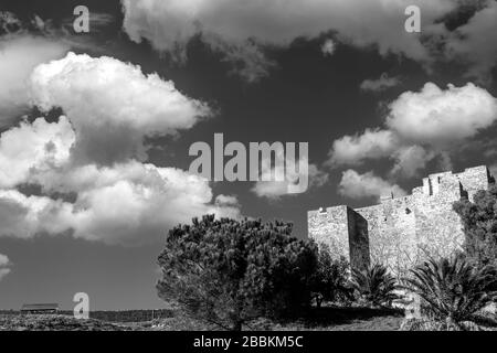 Die Rocca Aldobrandesca von Talamone, Grosseto, Toskana, Italien, gegen einen dramatischen und malerischen Himmel in Schwarzweiß Stockfoto