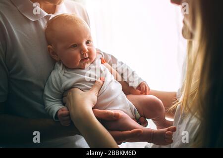 Mutter und Vater halten ein Baby in den Armen. Pflege und Gesundheit. Frohe junge Familie. Stockfoto