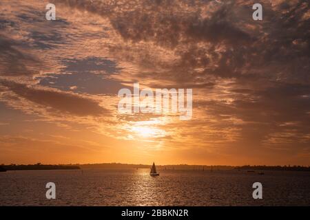 Feuriger Sonnenuntergang über dem Swan River, Perth West Australia. Idyllische Szene mit Segelbooten beim Dämmersegeln Stockfoto