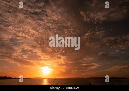 Feuriger Sonnenuntergang über dem Swan River, Perth West Australia. Idyllische Szene mit Segelbooten beim Dämmersegeln Stockfoto