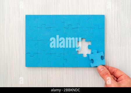 Hand das letzte Stück des Puzzles zur Vollendung der Aufgabe Stockfoto