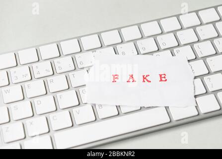Word Fake auf zerrissenem Papier auf einer Computertastatur geschrieben Stockfoto