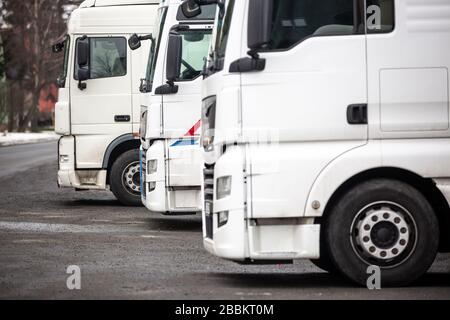 Weiße LKWs warten in Folge auf das Beladen von Material, Logistikkonzept Stockfoto