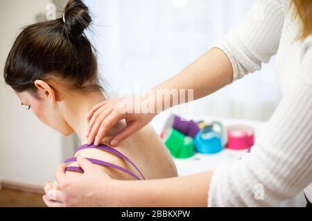 Professioneller körperlicher Therapeut, der Klebeband auf der Schulter des Patienten anwendet, kinesiotaping Konzept Stockfoto