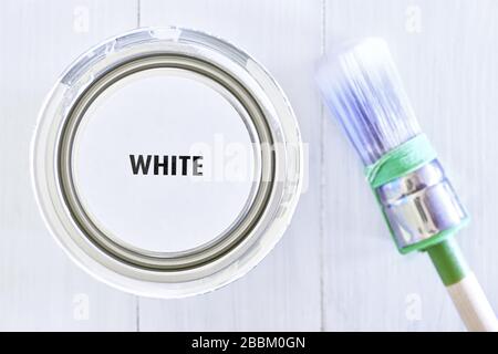 Farbe kann auf frisch lackiertem weißem Holzhintergrund und Bürste mit Grün aufgetragen werden. Lacke mit Deckel und Text weiß in Schwarz. Hausmakeover. Stockfoto