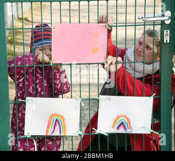 Leipzig, Deutschland. März 2020. In der Kindertagesstätte Fuchsbau des DRK-Kreisverbandes Leipzig hängen die Erzieherin Sarah und die vierjährige Paula Bilder, die von Kindern gemalt wurden, am Eingang der Einrichtung an. Die Kindertagesstätte ist eine der vielen Einrichtungen, die für die Notfallversorgung von Kindern sorgen, deren Eltern von sechs bis 17 Uhr in systemwichtigen Arbeitsstellen beschäftigt sind. Kredit: Waltraud Grubitzsch / dpa-Zentralbild / ZB / dpa / Alamy Live News Stockfoto