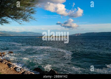 Insel San Marino und kleine Kapelle vor dem Ufer von Novi Vinodolski, an der kroatischen Seite der adriatischen Küste bei Sonnenuntergang Stockfoto