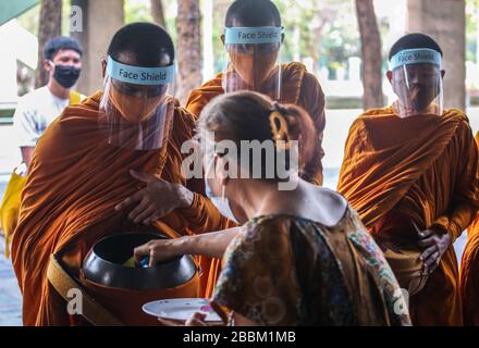 Thailändische Mönche, die Schutzmasken als präventive Maßnahme gegen die Ausbreitung der COVID-19-Pandemie tragen, erhalten Almosen in Bangkok. Das thailändische Ministerium für öffentliche Gesundheit berichtet von 120 neuen Fällen von Coronavirus (Covid-19), wodurch die Gesamtzahl auf 1.771 und 12 Todesfälle angehoben wird. Stockfoto