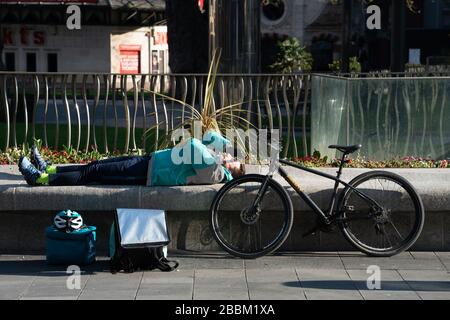 Ein Fahrer von Deliveroo macht eine Pause in einem fast menschenleeren Leicester Square im Zentrum Londons, nachdem die Regierung eine teilweise Sperrung in Großbritannien erklärt hatte. Phot Stockfoto